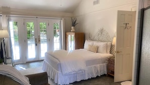 A bedroom with a large bed, a sofa, a dresser, and a door leading to a balcony. - Beaufort House Inn (Asheville)