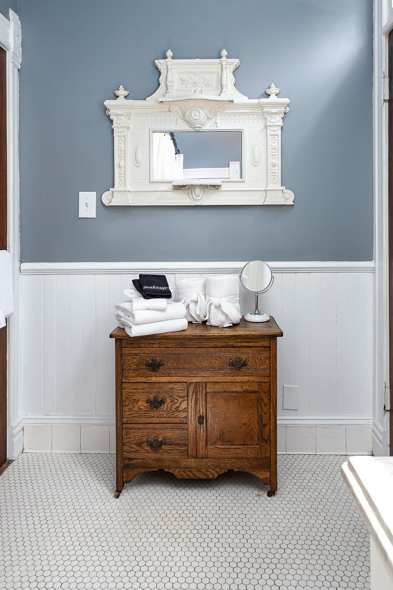 A bathroom with a vanity, a mirror, and toiletries.