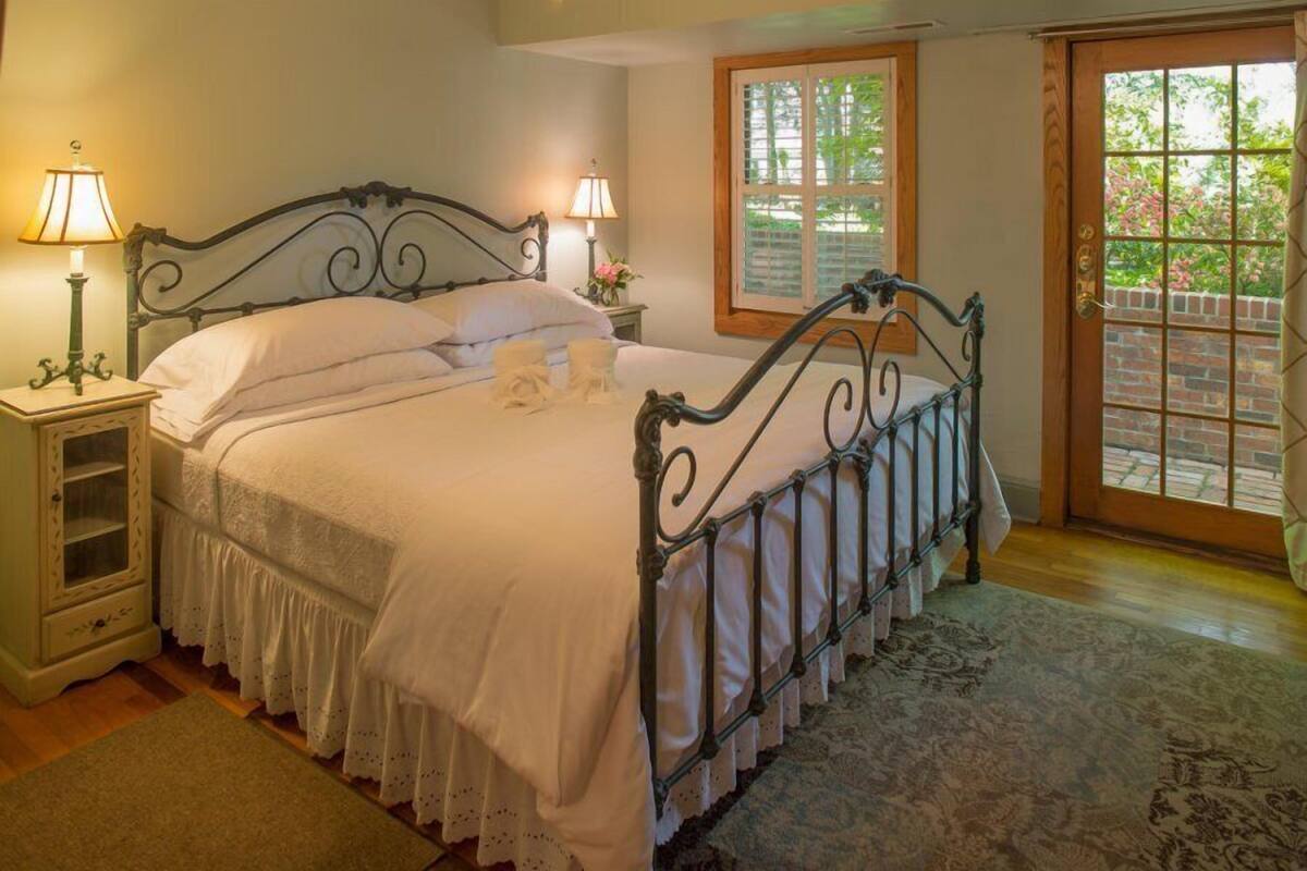 A neatly made bed with white linens, a metal headboard, and two bedside lamps.
