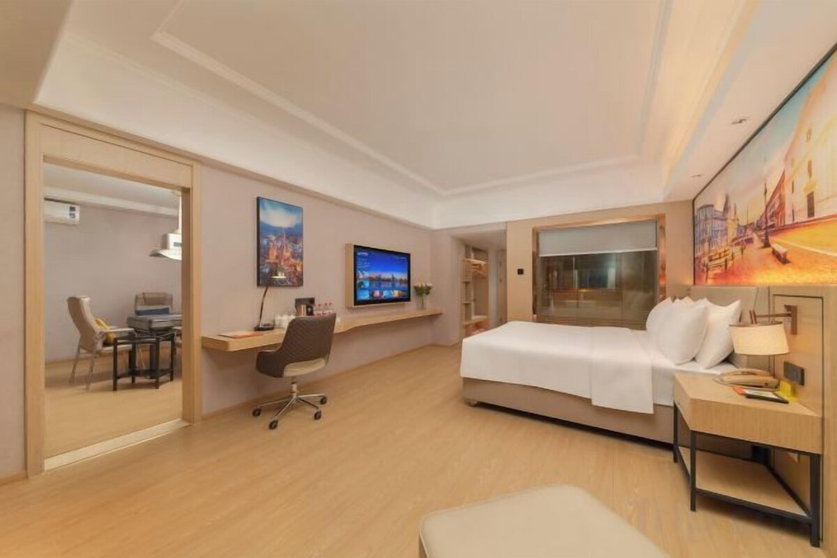 Una habitación de hotel con cama, escritorio, silla y televisor.