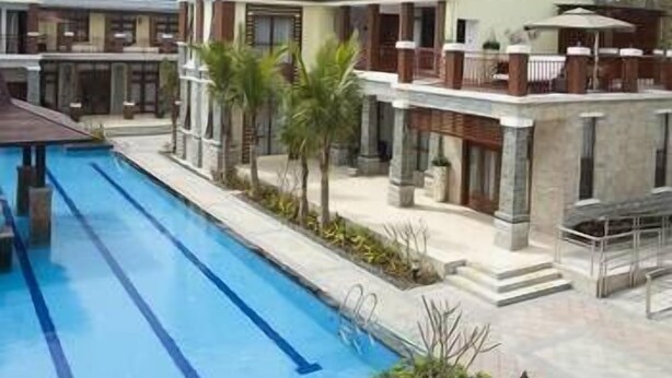 A hotel with a swimming pool, multiple buildings, and a tropical garden. - Lanyang Geology Hot Spring Resort (Danzhou)