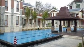 A swimming pool with a lifeguard chair, surrounded by buildings with a mix of modern and traditional architecture. - Lanyang Geology Hot Spring Resort (Danzhou)