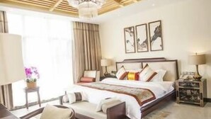 A hotel room with a large bed, a desk, and a chair. There is a chandelier above the bed and a painting on the wall. - Lanyang Geology Hot Spring Resort (Danzhou)