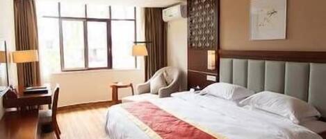 A hotel room with a bed, a desk, a chair, and a window with curtains.