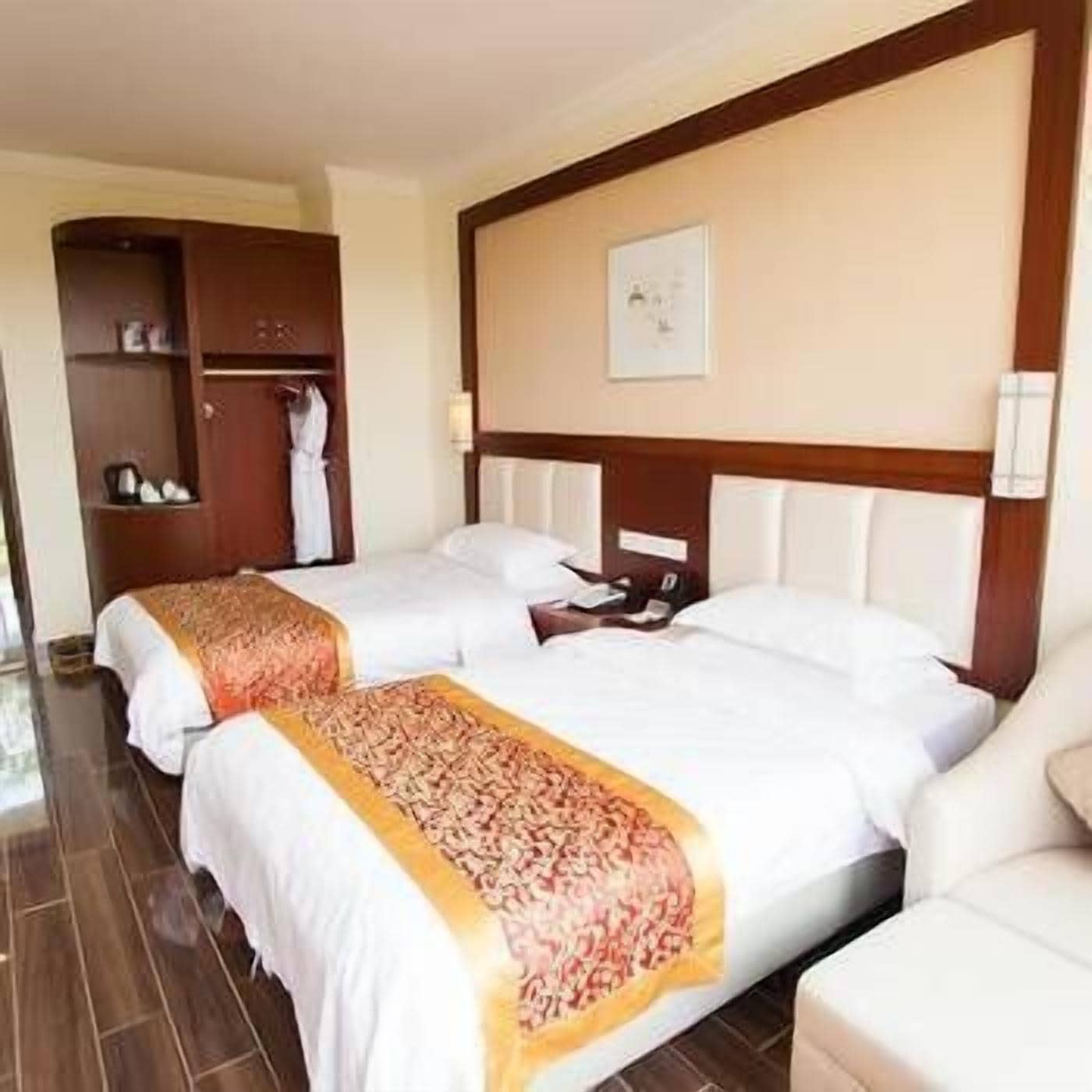 Een hotelkamer met twee bedden, een garderobe en een ingelijst kunstwerk aan de muur.
