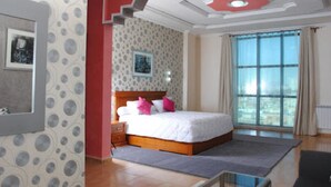 Una camera da letto con un letto grande, un comodino, un quadro incorniciato, una finestra con tende e una parete decorata.