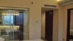 A hotel room with two beds, a glass partition, and a view of the city. - Guifeng Hotel (Jiangmen)