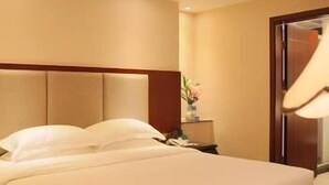 A hotel room with a large bed, a nightstand, and a lamp. - Guifeng Hotel (Jiangmen)