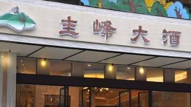 A hotel entrance with a sign in Chinese characters, a glass door, and a red carpet leading inside. - Guifeng Hotel (Jiangmen)