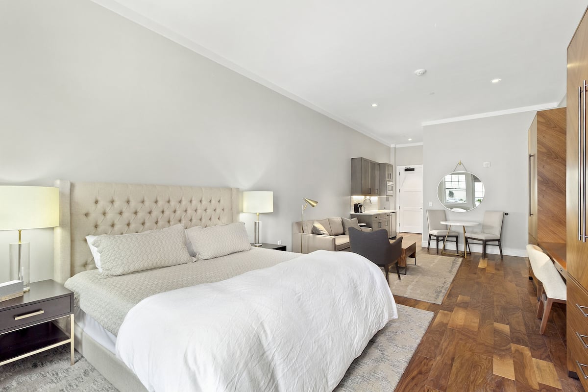 A modern bedroom with a large bed, bedside tables, a desk, and a wardrobe.