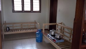 Una habitación pequeña y sencilla con un banco de madera, un cilindro de gas y una hornilla portátil.