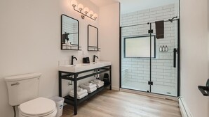 A modern bathroom with a white toilet, black sink, and a glass shower enclosure. - Uplift Inn (Idaho Springs)