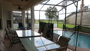Un patio couvert avec une piscine, des sièges d’extérieur et une vue sur le paysage environnant.