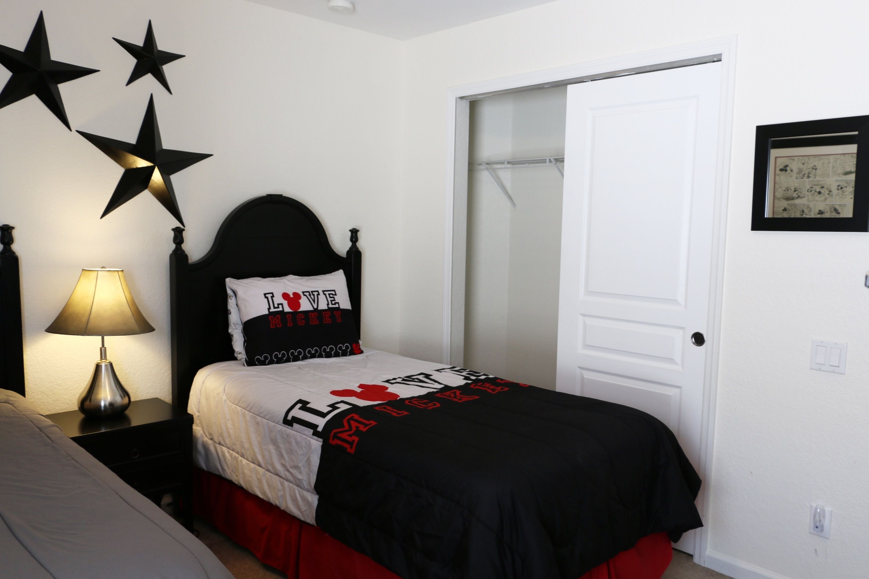 A bedroom with a bed, a nightstand, a lamp, and a door.