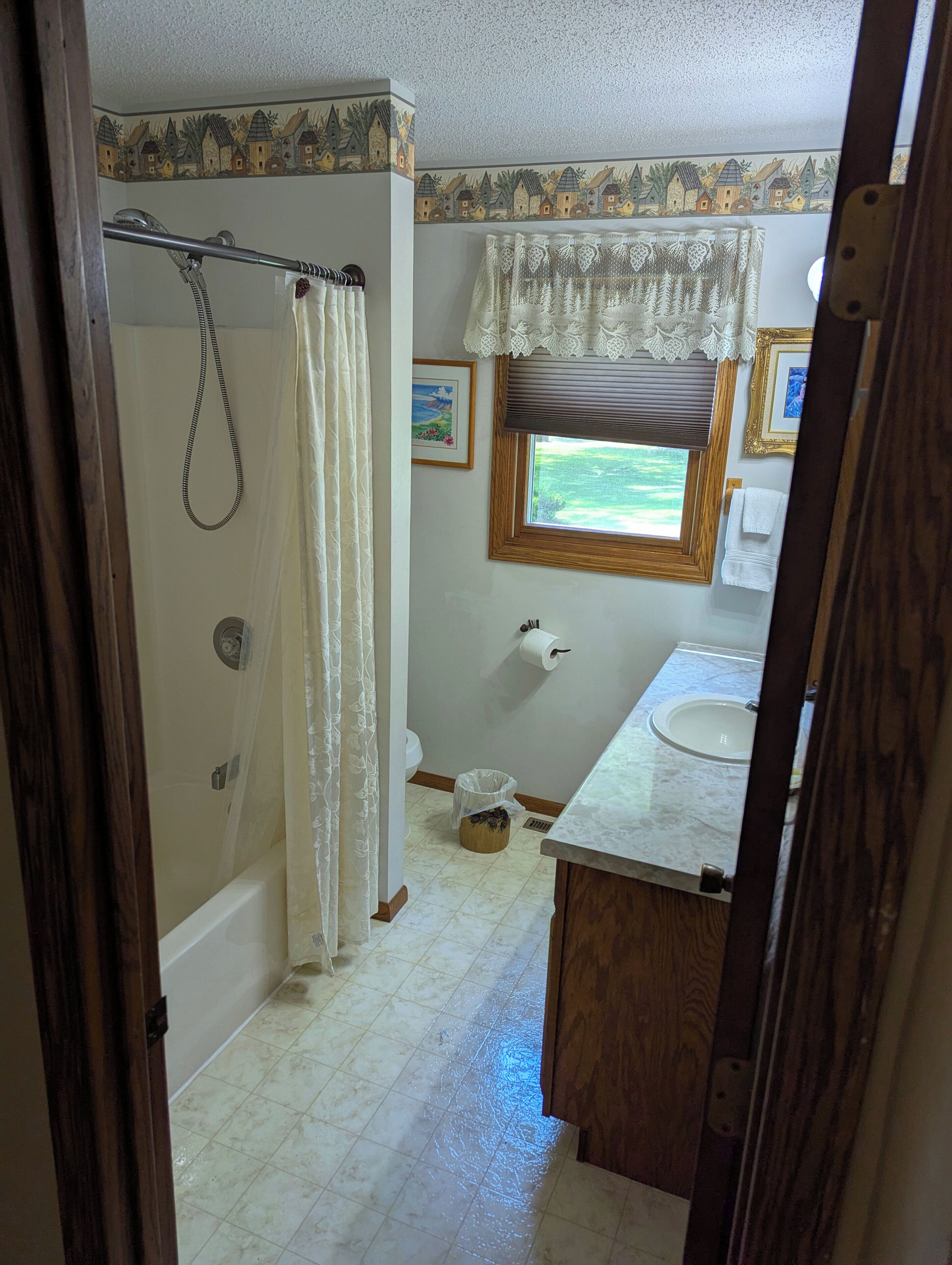 Une salle de bain avec douche, toilettes, lavabo et une fenêtre donnant sur un beau paysage.