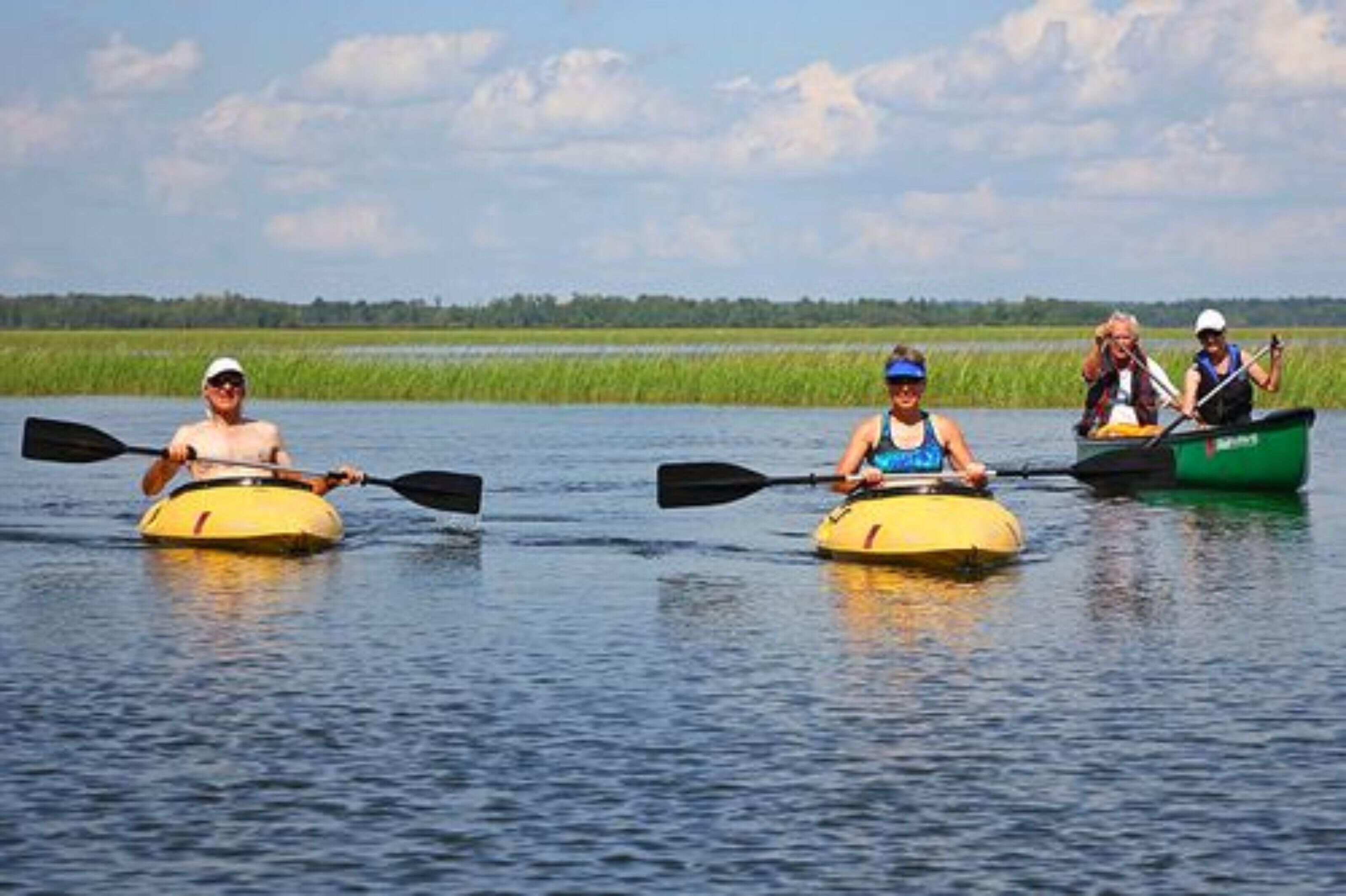 Three people kayaking on a calm river.