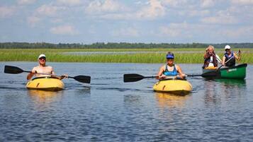 Three people kayaking on a calm river.