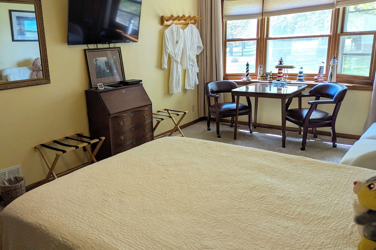 A hotel room with a bed, a desk, two chairs, a television, and a window with a view.