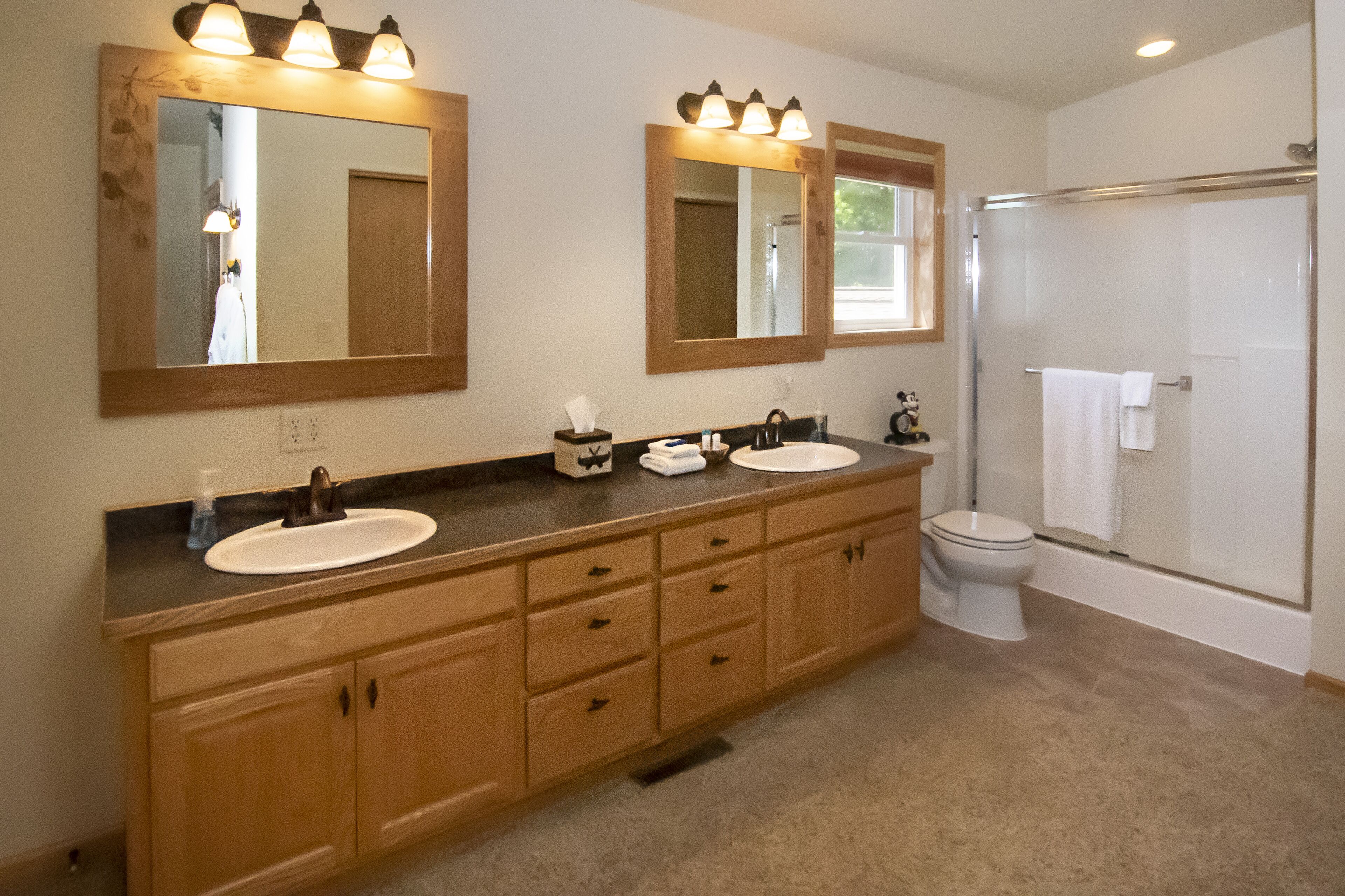 A bathroom with two sinks, a toilet, and a shower.