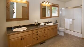 A bathroom with two sinks, a toilet, and a shower.