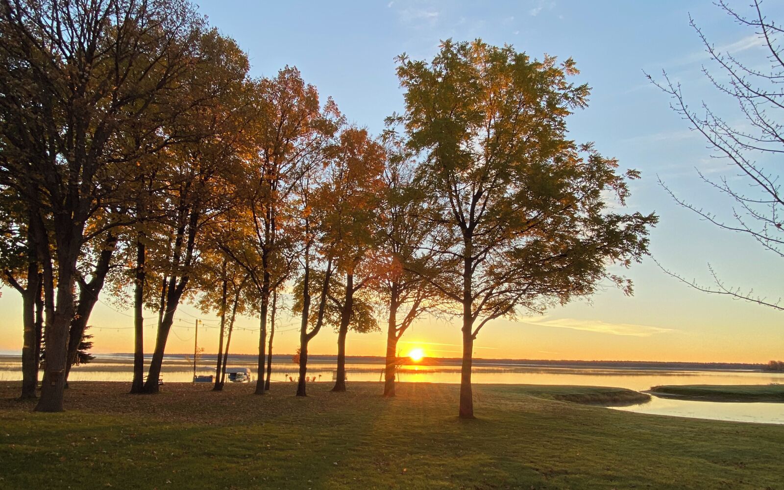A serene lakeside view with trees and a sunset.