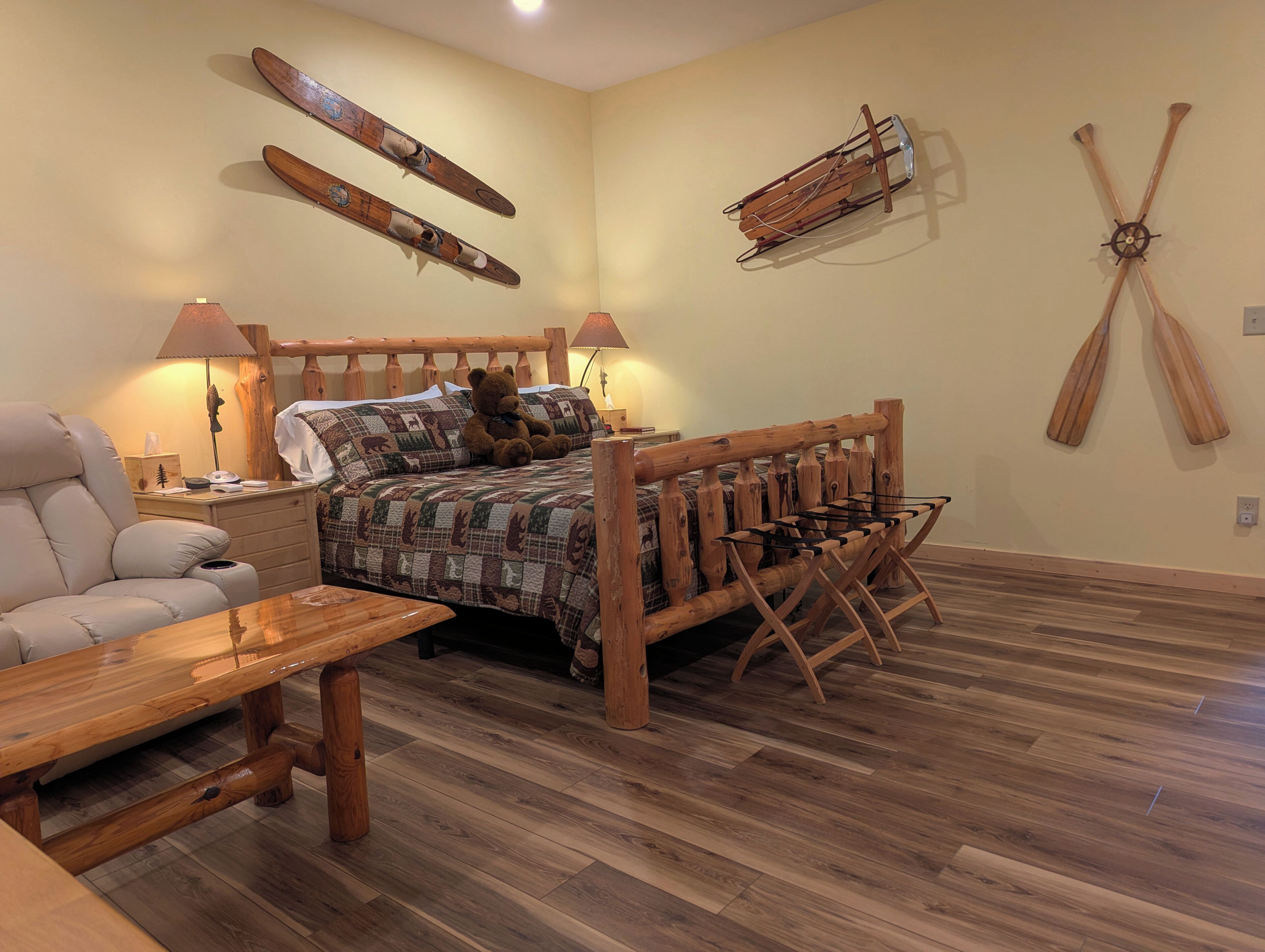 Una habitación con una cama y una mesa de madera, y esquíes y una pala en las paredes.