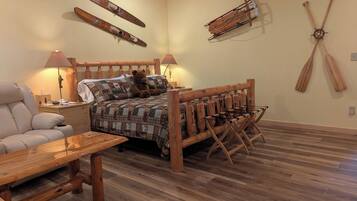Una habitación con una cama y una mesa de madera, y esquíes y una pala en las paredes.
