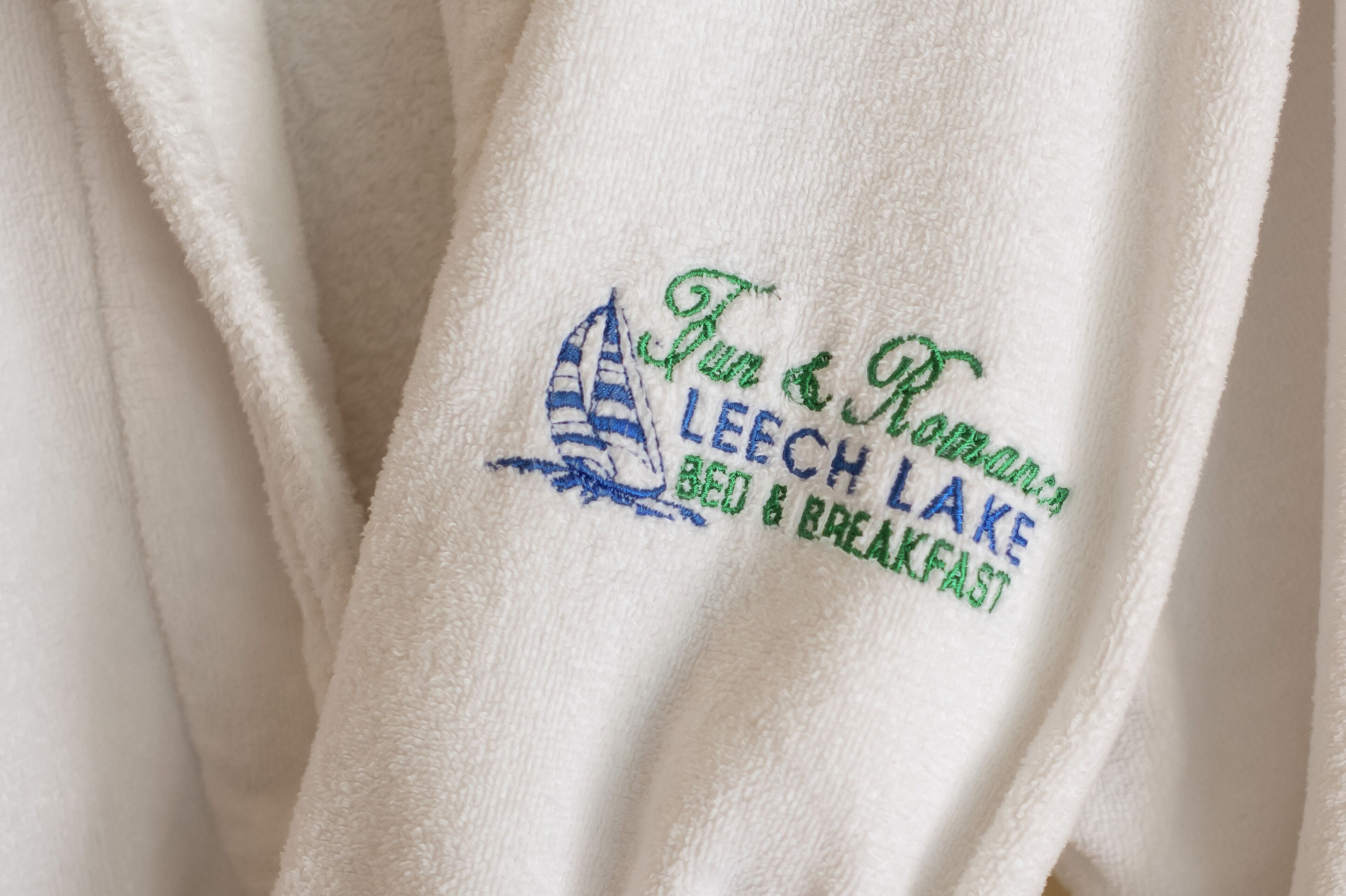 A white towel with embroidered text and a sailboat design.