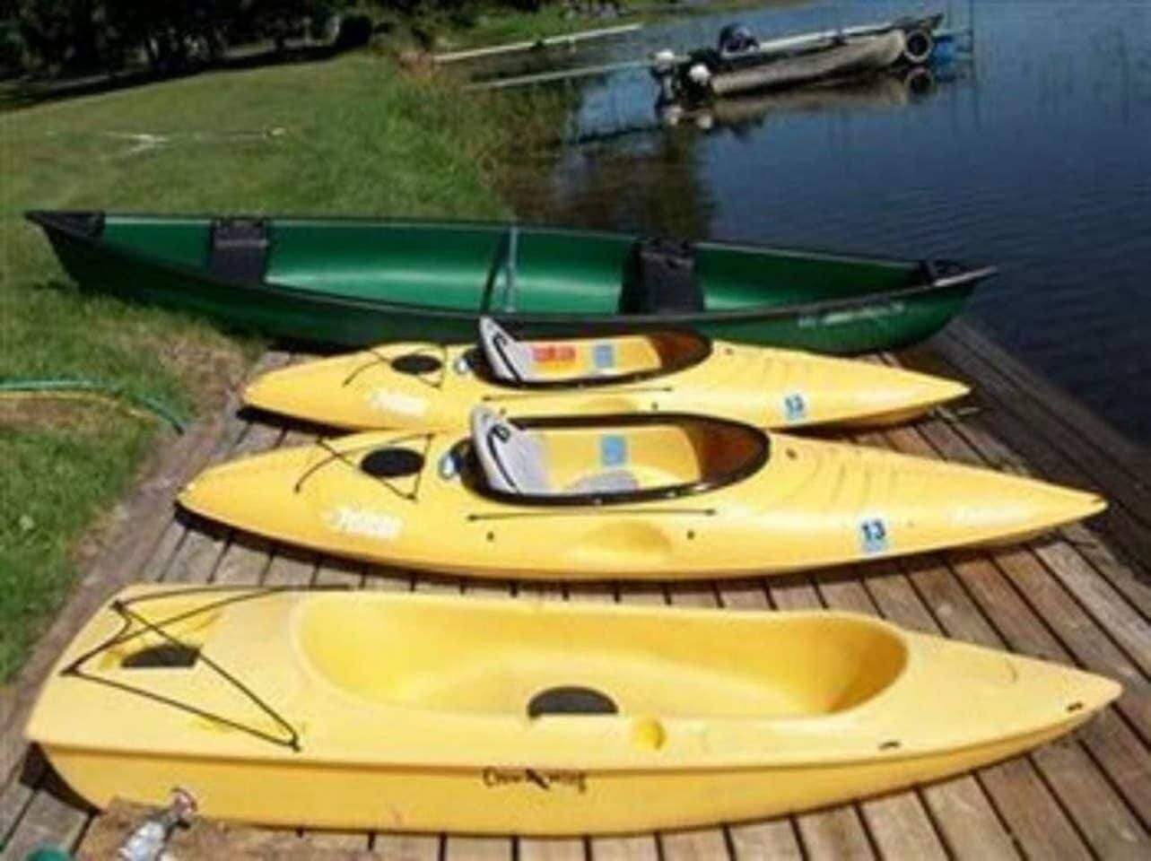 Three kayaks on a wooden dock by a calm body of water.