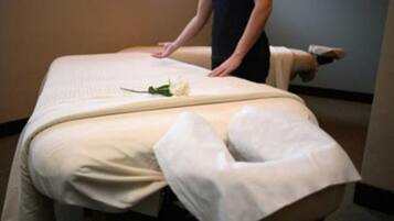 Experience a serene massage in a tranquil space with a massage table, white rose, and soothing ambiance.