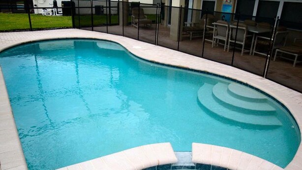 A swimming pool with a tiled edge and a hot tub in the foreground. - 6BR 4BA Home in Windsor Hills by CV-2564 (Kissimmee)