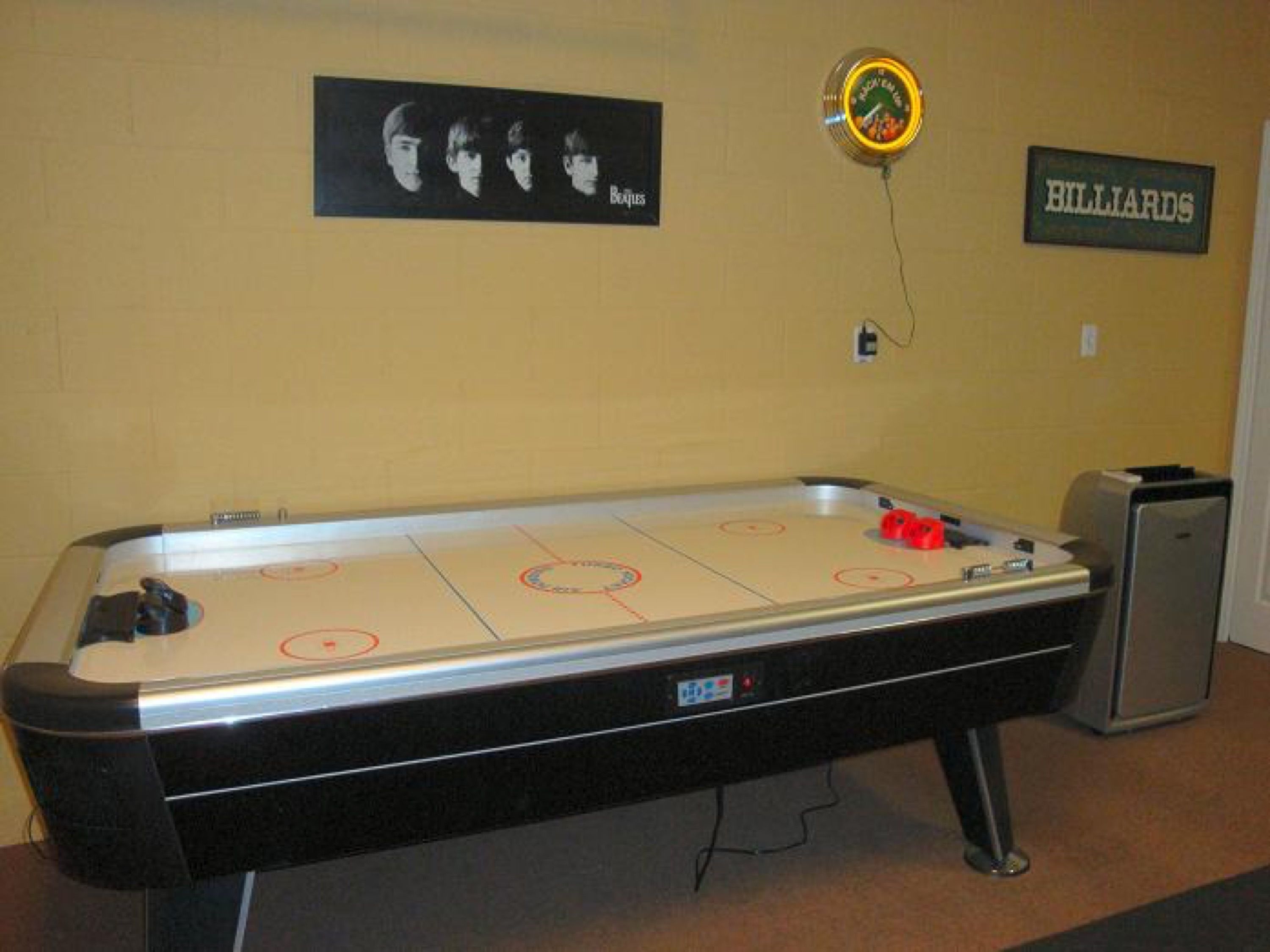 A pool table with a clock and a billiards sign on the wall.