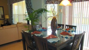 A dining area with a glass table, dark wooden chairs, and a vase centerpiece. - 6BR 4BA Home in Windsor Hills by CV-2564 (Kissimmee)