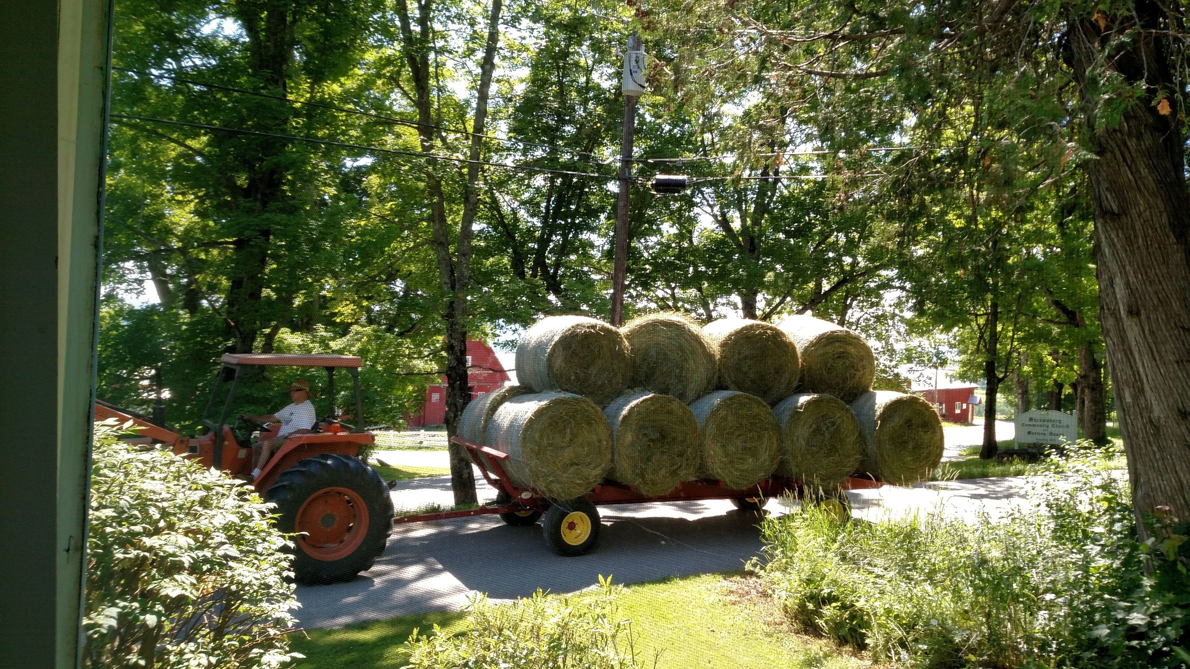 Un tractor remolcando un remolque cargado con fardos de heno.
