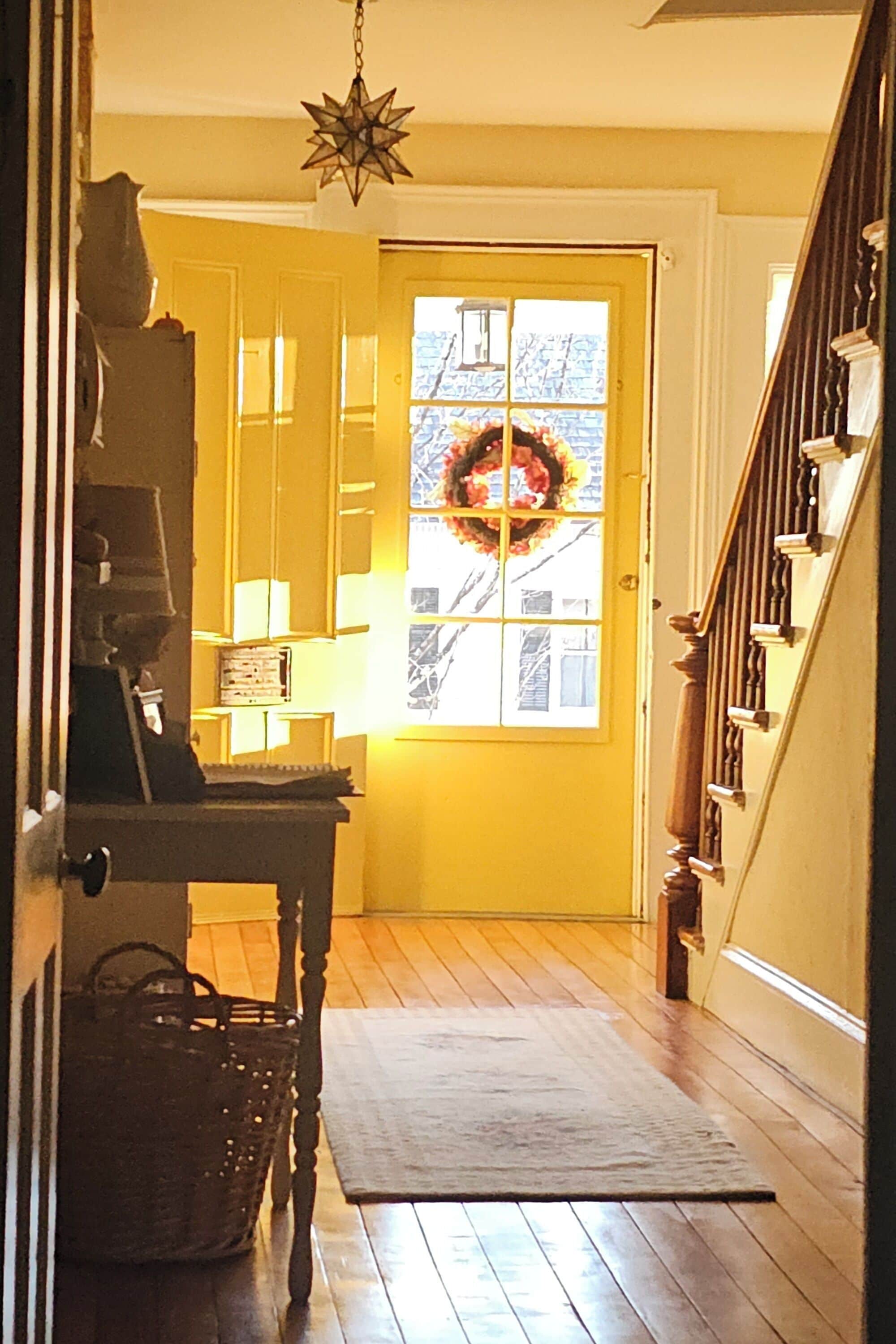 A wooden staircase leading to a yellow door with a wreath.