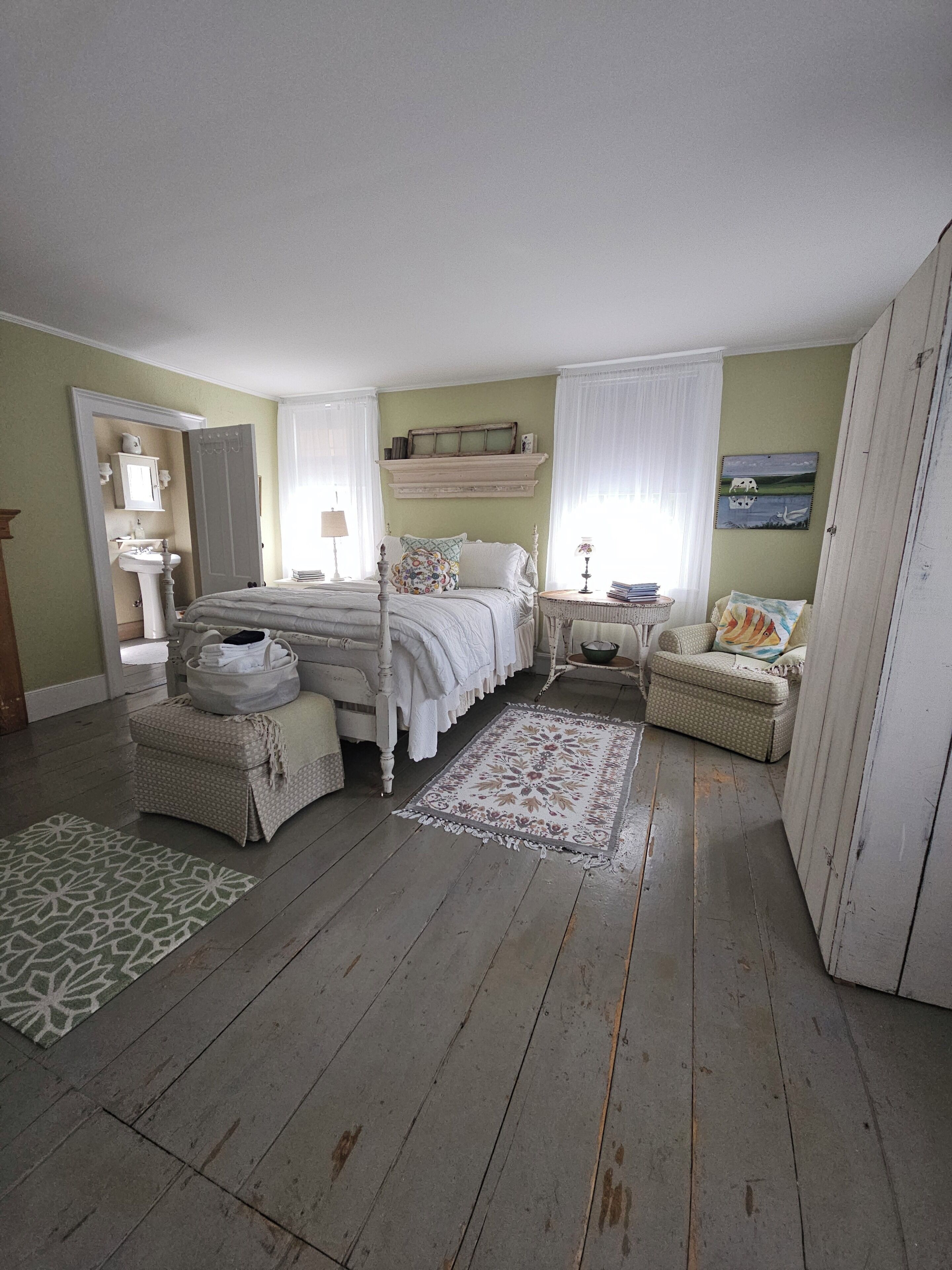 Una camera da letto con un letto, un comodino, una sedia, un tavolino, uno specchio, uno scaffale e un armadio.