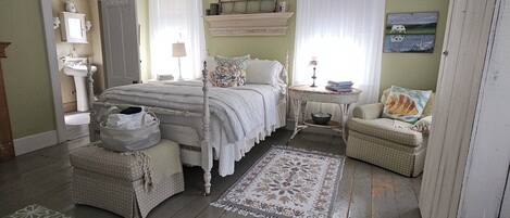 Una camera da letto con un letto, un comodino, una sedia, un tavolino, uno specchio, uno scaffale e un armadio.