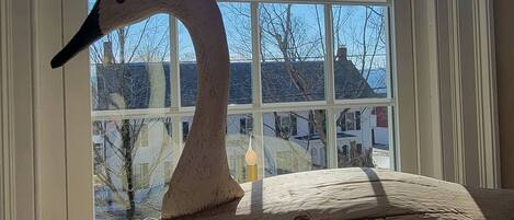 A swan-shaped object on a windowsill with a view of houses and bare trees outside.