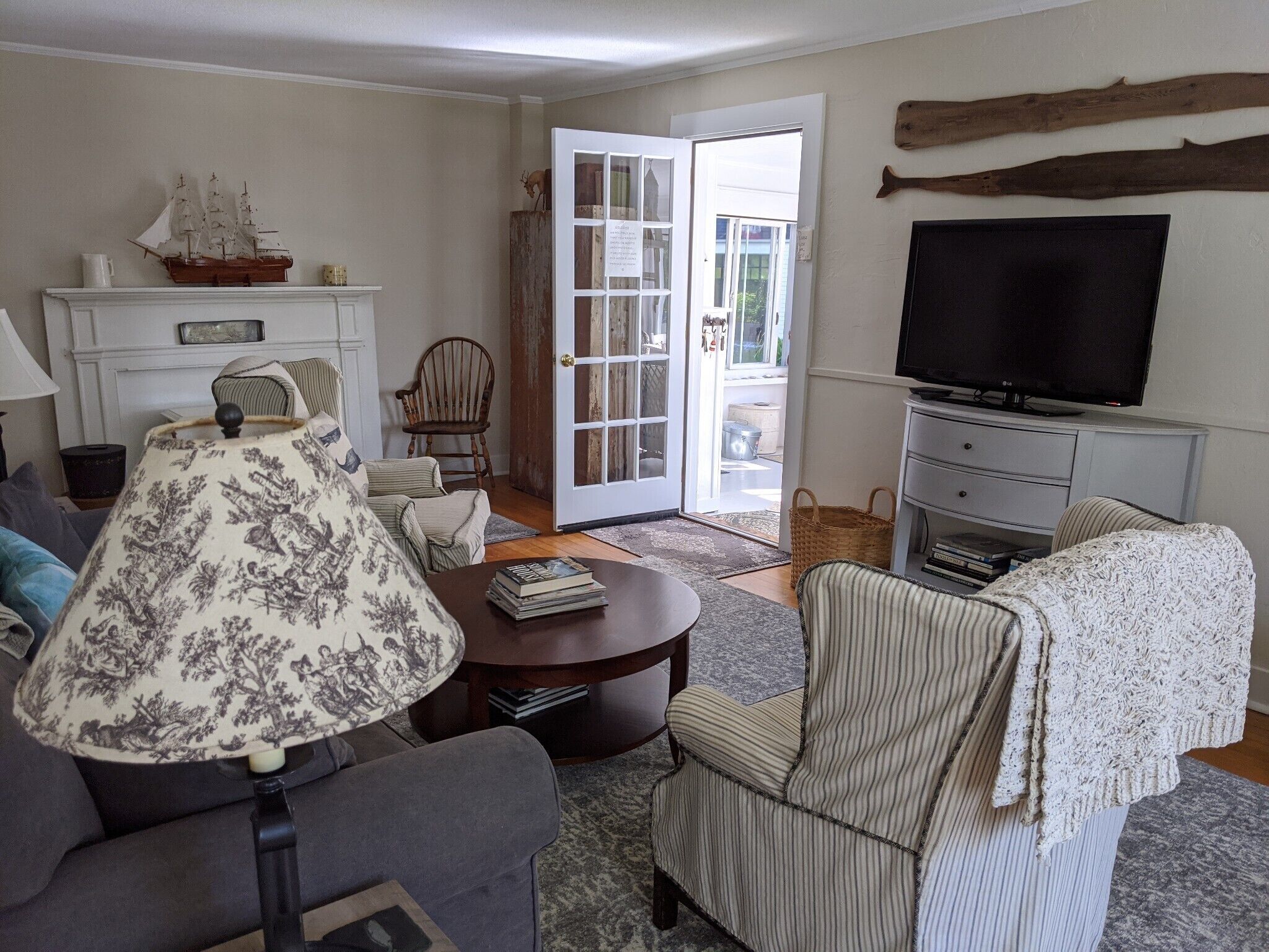 A living room with a sofa, armchair, coffee table, lamp, television, and a bookshelf.