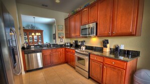 A kitchen with wooden cabinets, stainless steel appliances, and a tiled floor. - 5BR 5BA Home in Windsor HIlls by CV-2622 (Kissimmee)
