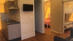 A compact room with a kitchenette, a bed, and a sleeping area. - Vento Etrusco - Camping (Piombino)