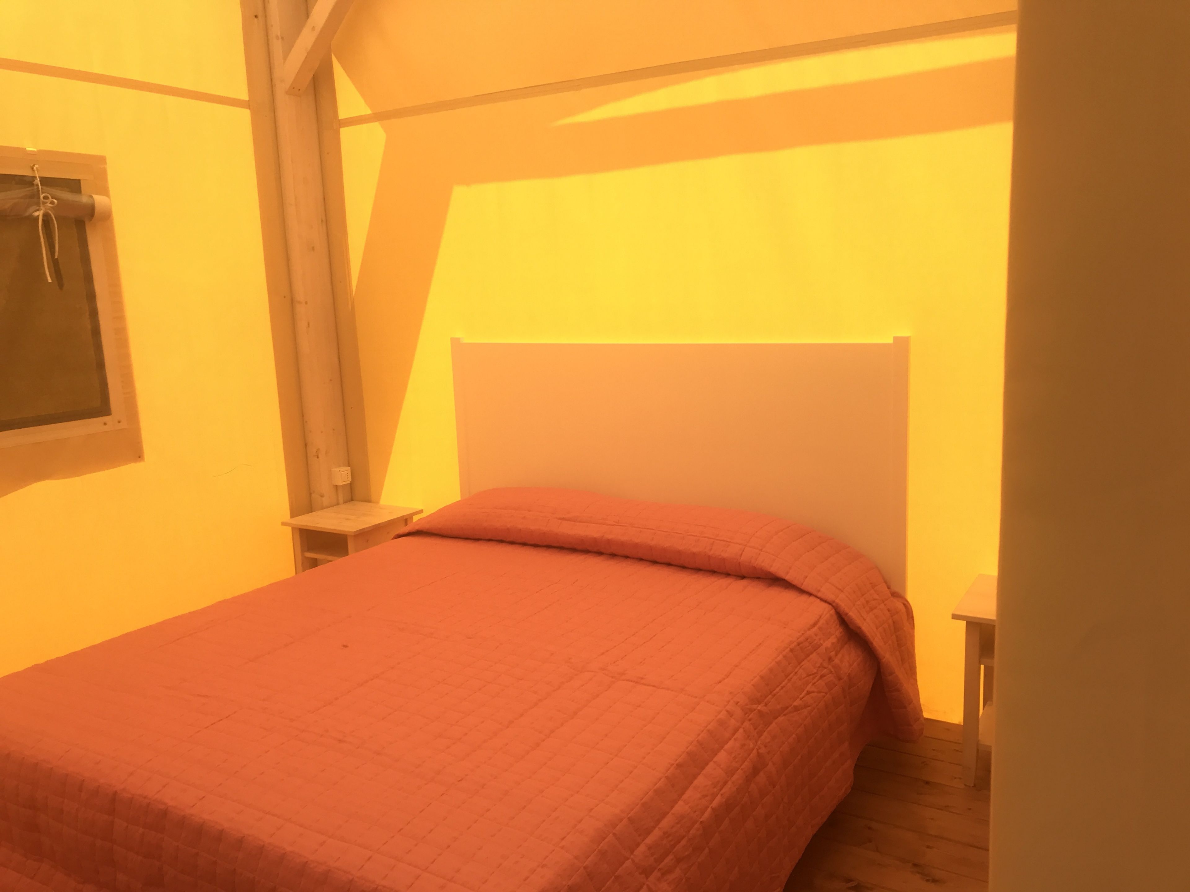 Un letto singolo con una testiera in legno in una stanza con soffitto spiovente.