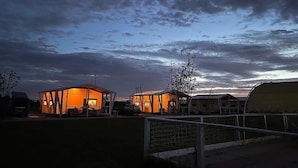 A building with a large open space and a smaller enclosed area, both illuminated by warm lighting. - Vento Etrusco - Camping (Piombino)