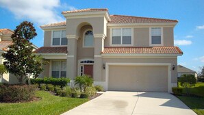 A two-story house with a tiled roof, a front garage, and a well-maintained lawn.