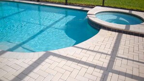 A swimming pool with a paved deck and a small hot tub area.