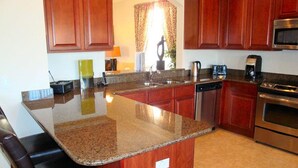 A kitchen with granite countertops, wooden cabinets, a stainless steel dishwasher, and an oven.
