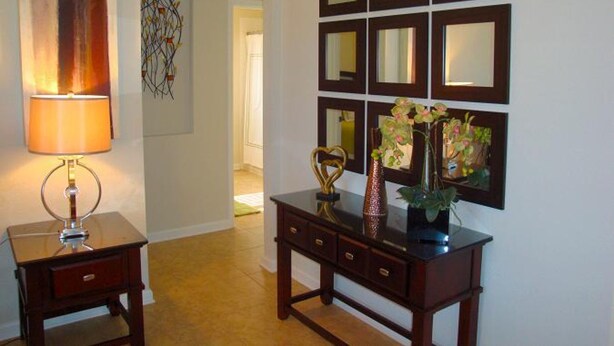 A hallway with a lamp, a decorative wall piece, and a mirror display.