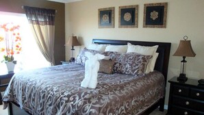 A neatly made bed with a patterned bedspread, a bedside table with a lamp, and three framed pictures on the wall.