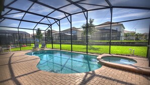 A swimming pool with a covered area, surrounded by a brick patio and a view of a residential neighborhood. - 6BR 4BA Home in Windsor Hills by CV-2579 (Kissimmee)