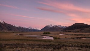 A panoramic view of a mountainous landscape with a river and snow-capped peaks. - The Lindis (Birchwood)